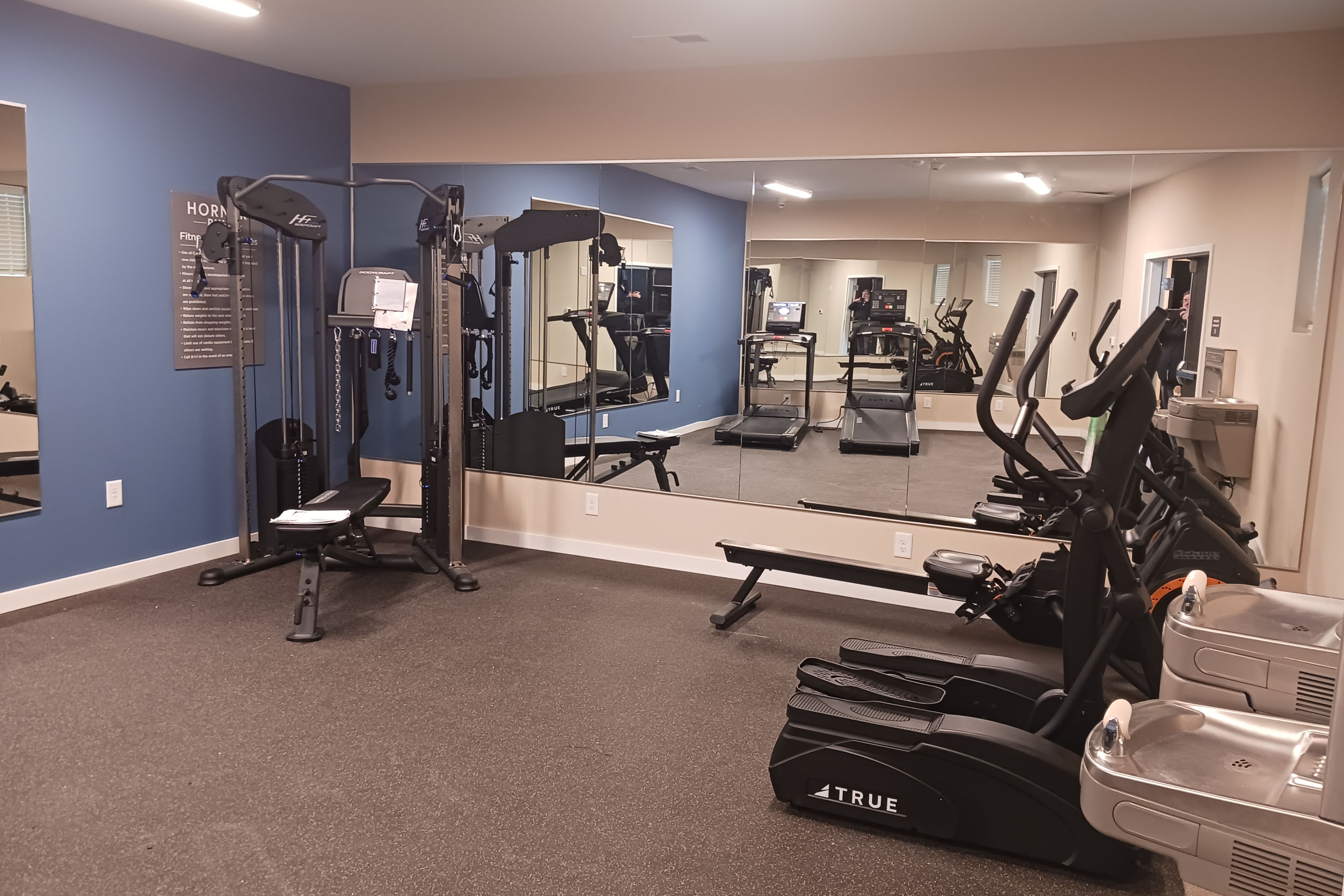 Apartment fitness center with workout equipment and mirrored wall.